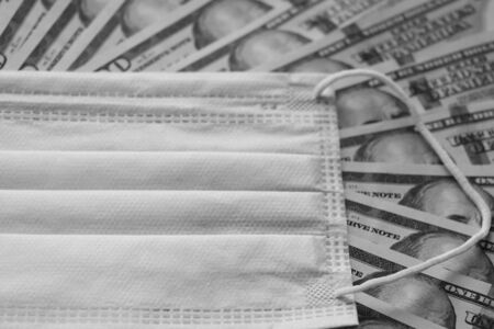 Medical mask on dollars as a symbol of increasing prices for protecting the respiratory tract from the virus. There is a place for copyspaceの写真素材