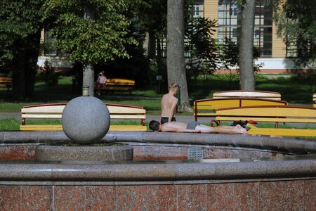 Children sunbathe in the sun near the fountainの写真素材