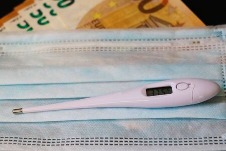 Disposable surgical mask, thermometer, euro banknotes. Reducing the risk of infection. Airborne...