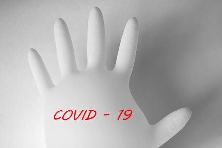 Medical glove on a white background with the text COVID - 19. Pandemic, coronavirusの写真素材