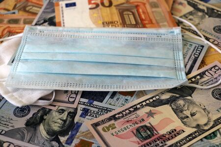 Medical mask on dollars and euro as a symbol of increasing prices for protecting the respiratory tract from the virus. There is a place for copyspaceの写真素材