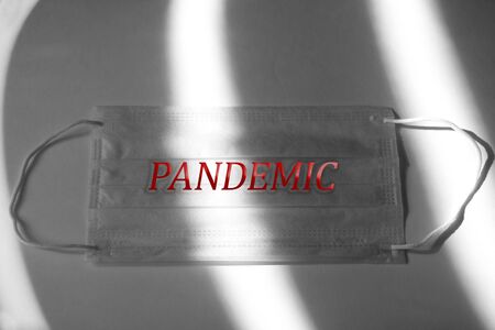 Dramatic atmosphere with surgical mask. Inscription PANDEMIC on a medical mask. Global pandemic alertの写真素材
