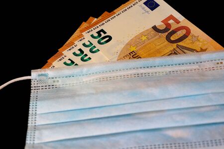 Coronavirus. Medical mask on top of US dollars and Euro. Global pandemic alertの写真素材