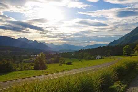 Mountain road leading to the village in the Austrian Alps. Beautiful alpine landscape with green meadowsの写真素材
