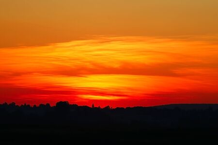 Sunset on the background of the field, the silhouette of the villageの写真素材