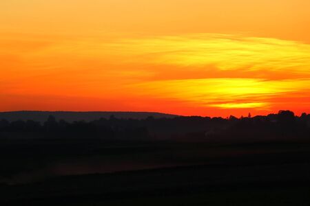 Sunset on the background of the field, the silhouette of the villageの写真素材