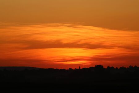 Sunset on the background of the field, the silhouette of the villageの写真素材