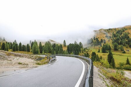 Slippery wet road high in the mountains. Misty morning in the Dolomites. Italy. Selective focusの写真素材