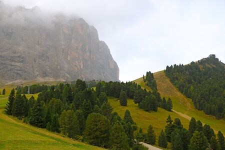 The peaks of the Dolomites in Italy are covered in fog. Early wet foggy morning. Beginning of autumn. Clean fresh air, lack of people. Selective focusの写真素材