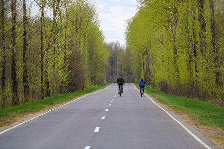 Two cyclists ride on an empty road into the distance. Selective focusの写真素材