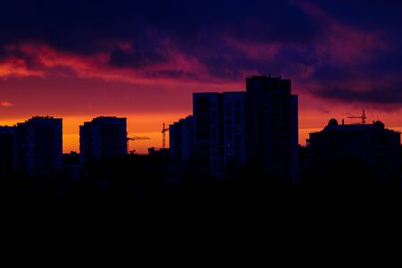 Beautiful sunset in the city. Silhouette of houses and construction cranes. Selective focusの写真素材