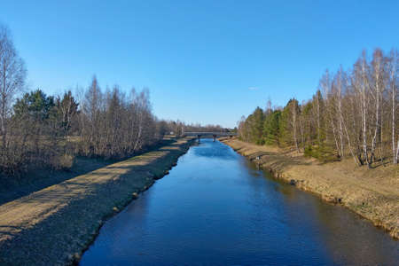 A small river along the forest in autumn or early spring