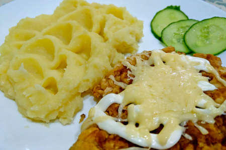 A piece of meat with mashed potatoes is on a white plateの写真素材