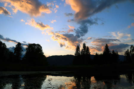 A beautiful epic sunset high in the mountains. Reflection of the sunset in the lakeの写真素材