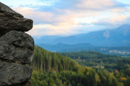 Close-up view of a part of a stone wall. Mountains and green forest out of focusの写真素材
