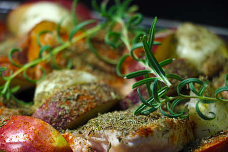 Green sprigs of rosemary on raw meat with apple slices for bakingの写真素材