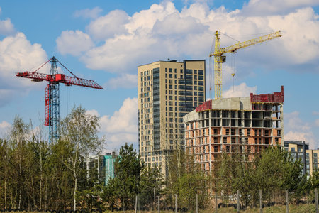 View of construction cranes and houses under constructionの写真素材
