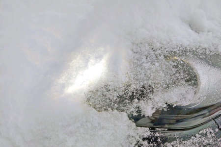 Snowy winter. The snow completely covered the car. Car headlight cleaningの写真素材