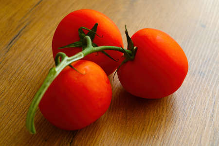 Close-up on a branch of red tomatoes on the tableの写真素材