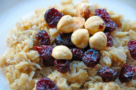 Plate with cooked oatmeal, hazelnuts and cranberries. Healthy foodの写真素材