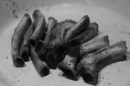 Black and white photo. Bones from meat on a plate