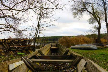 A broken wooden boat on the shore of the lake in the fallの写真素材
