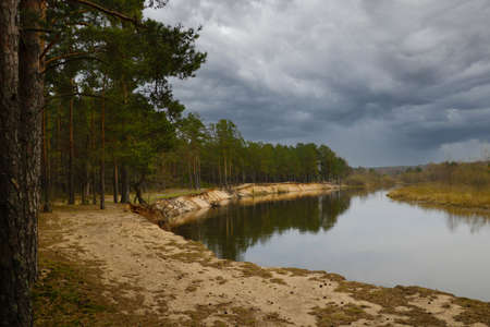 Cloudy autumn day on the river bank in the forestの写真素材