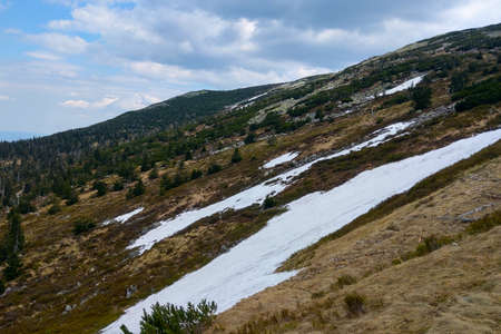 On the slope of the mountain lies snow in autumnの写真素材