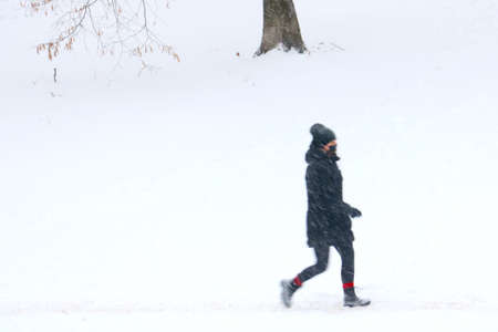 Out of focus, blurry background, a person goes on a snowy winter day. Bad weatherの写真素材