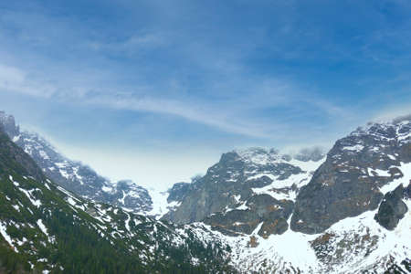 Picturesque view of the mountains with snow peaks against the blue sky.の写真素材
