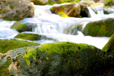 A blurred background, a river flows through the stones in the mountains.