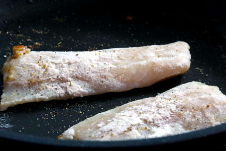 In a frying pan are fried pieces of fish, homemade food