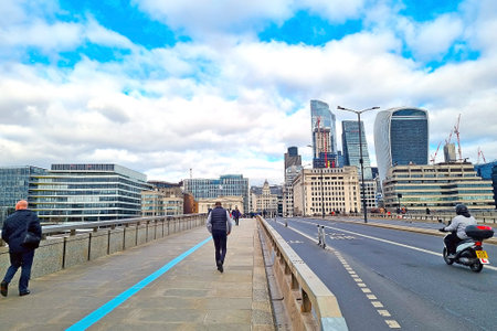 London, United Kingdom, February 8, 2022: people walk on the bridge and ride on transport against...