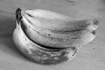 Black and white photo. A branch of delicious bananas on the table. Healthy food, fruitsの写真素材