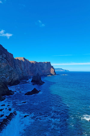 The blue water of the ocean and the mountainside. The coast of the islandの写真素材