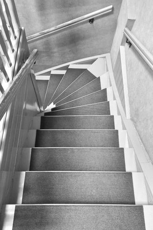 Black and white photo. Vertical photo of a wooden staircaseの写真素材