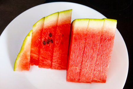 Juicy, fresh watermelon slices neatly arranged on a white plate. the vibrant red and green colors make it ideal for healthy eating themes, food photography, summer refreshment, culinary magazines, and recipe blogs seeking visually appealing content.の写真素材