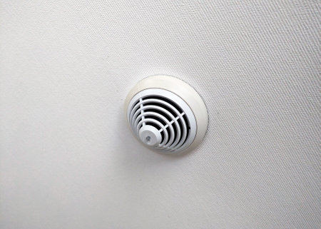 Wall-mounted smoke detector featuring a sleek design, enhancing home safety by providing early fire detection. the subtle elegant texture of the wall complements the device's modern aesthetic.の写真素材