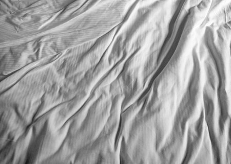 Crumpled white fabric showcasing texture and folds, ideal for minimalist backgrounds and design projects. the soft light and shadows create a sense of depth and subtlety, perfect for artistic or commercial applications.の写真素材