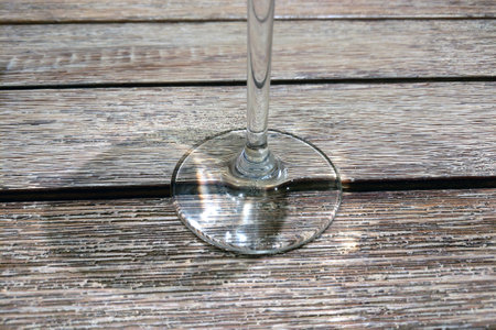 Elegant glass stemware beautifully contrasts with a rustic wooden table surface, creating a sophisticated dining scene. the interplay of light and shadow enhances the texture, perfect for concepts of elegance and style.の写真素材