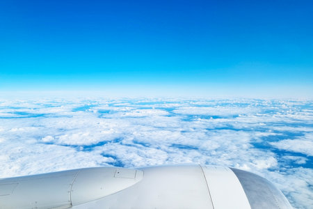 Stunning view of fluffy clouds from an airplane window, showcasing a serene sky and vast horizon. the image conveys a sense of freedom and adventure, ideal for travel inspiration and aviation themes.の写真素材