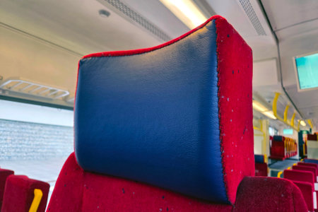 Focused view of a padded headrest in a train carriage, the vibrant blue and red color combination. the modern public transportation setting emphasizes comfort and style in travel.の写真素材