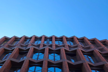 Geometric patterns form the striking facade of a contemporary building, contrasting against a clear...