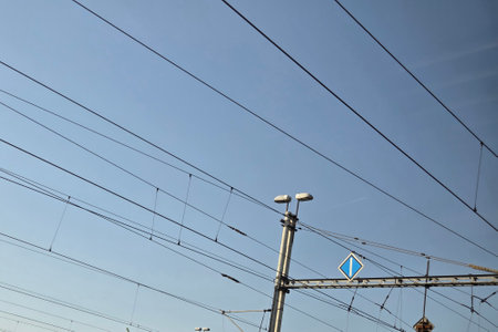 Overhead power lines stretching across a clear blue sky highlight urban infrastructure and...