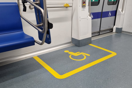 Interior of a public transit vehicle showcasing a dedicated wheelchair space marked by a yellow...