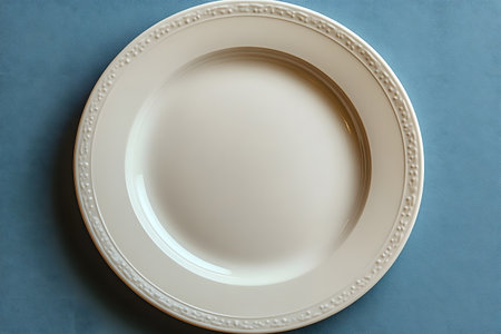 A sophisticated white ceramic dinner plate with intricate detailing along the rim set against a soft blue background. the minimalist design and neutral colors complement a variety of culinary and dining themes. Generative AIの素材