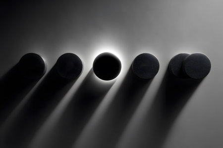 Circular objects cast dramatic shadows under focused lighting on a smooth surface, creating an abstract and minimalist composition. the interplay of light and shadows emphasizes the geometric simplicity and visual depth. Generative AIの素材