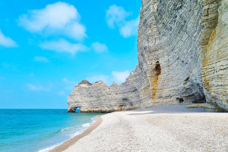 A stunning view of towering coastal cliffs meeting a tranquil beach under a vibrant blue sky. the...