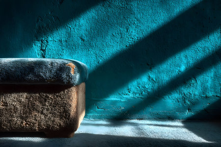 Rustic wooden bench in a tranquil setting, bathed in sunlight streaming through unseen windows. the textured blue wall adds depth and contrast, creating a peaceful atmosphere perfect for interior design themes. Generative AIの素材