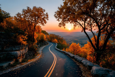 A winding road meanders through a forest ablaze with autumn colors as the sun sets on the horizon, casting warm light over the landscape. the serene scene captures nature's tranquil beauty and invites admiration. Generative AIの素材